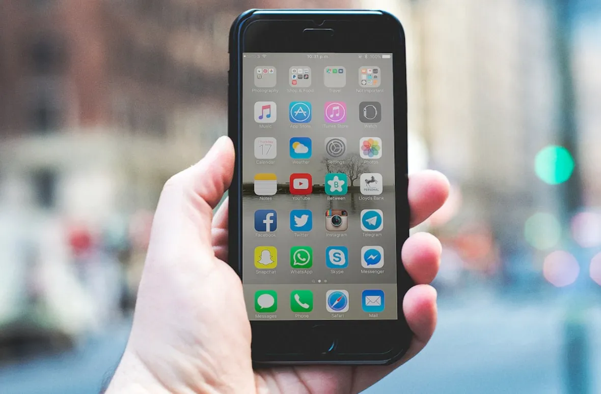 A hand holding a phone with social media apps on display.