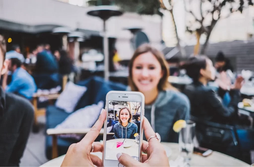 A phone capturing a smiling person in a social gathering.